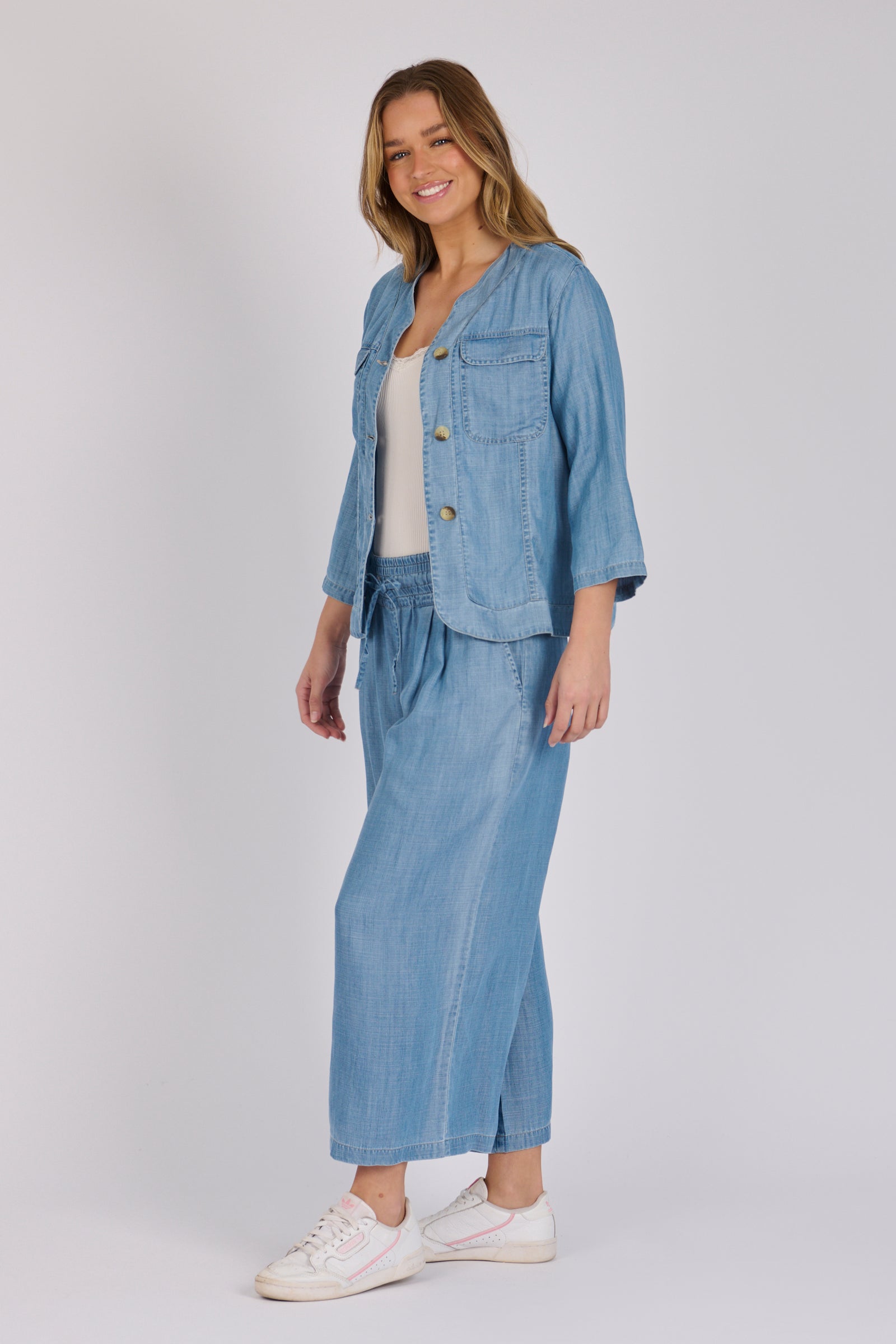 Woman wearing a light blue 100% lyocell utility jacket with patch pockets and a collarless neckline.