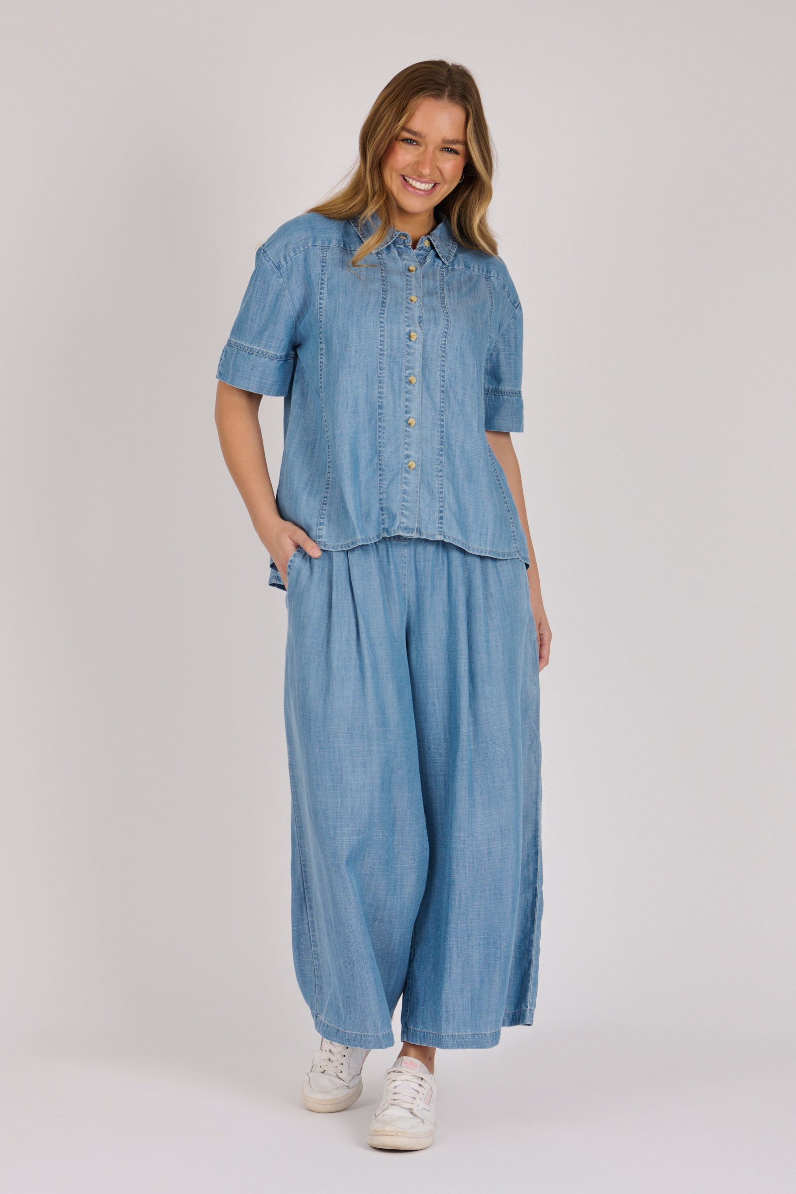 Woman wearing a white 100% lyocell short sleeve button-through shirt with cuffed sleeves and front panel detailing.