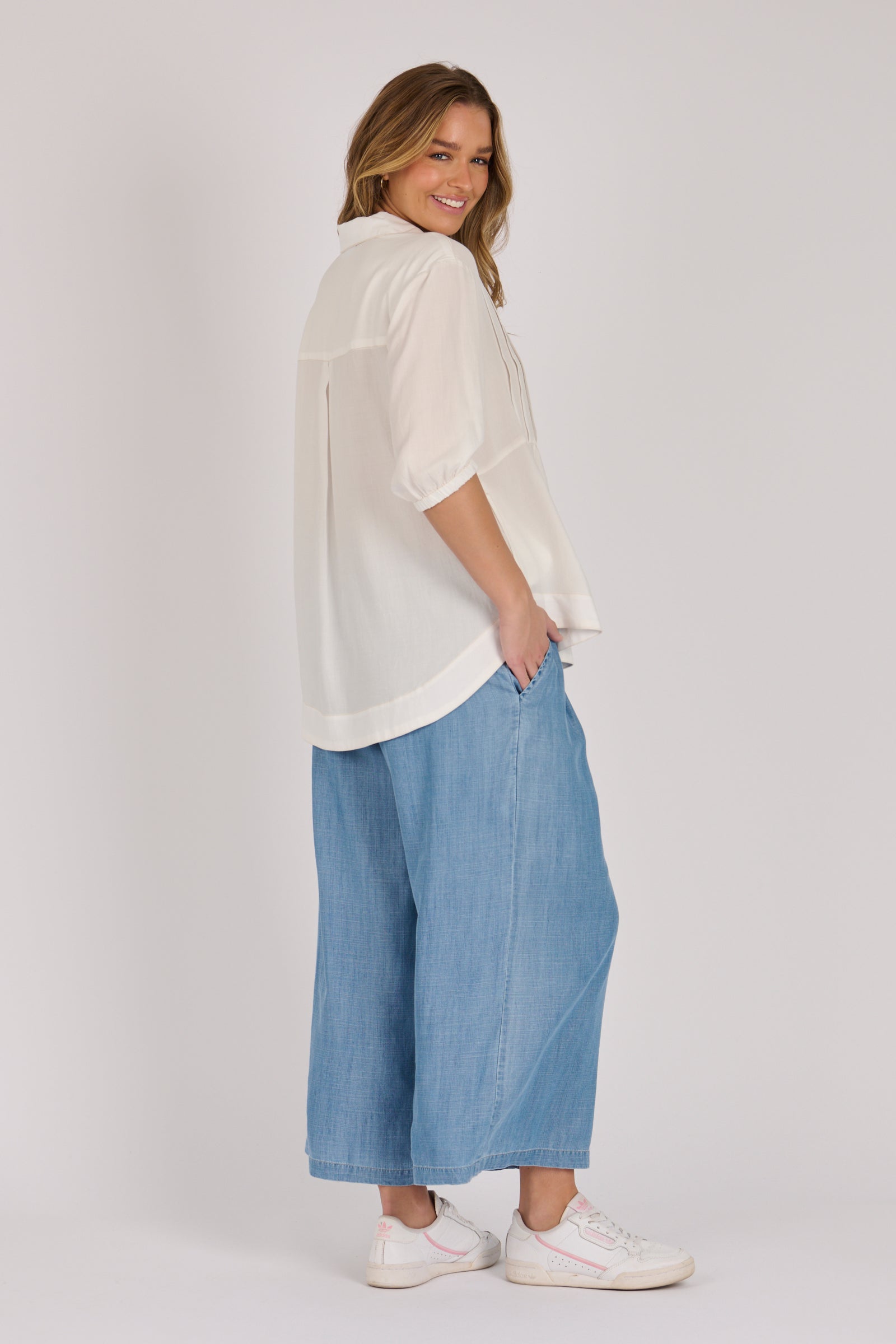 Woman wearing a white 100% lyocell gathered waist blouse with vertical panel detailing, 3/4 elasticated sleeves and a button-through front.