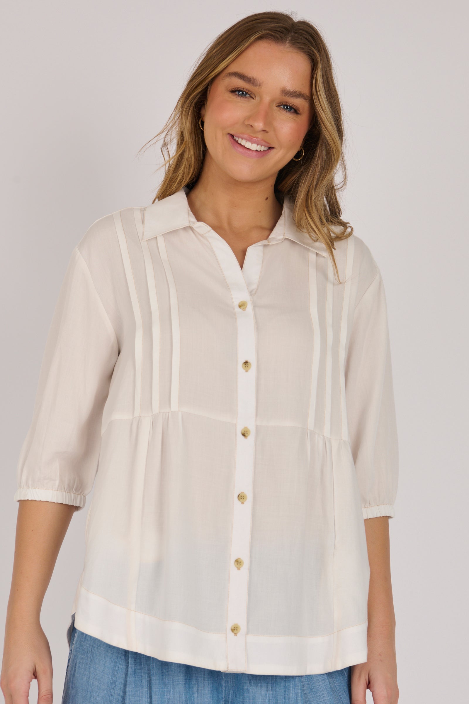 Woman wearing a white 100% lyocell gathered waist blouse with vertical panel detailing, 3/4 elasticated sleeves and a button-through front.