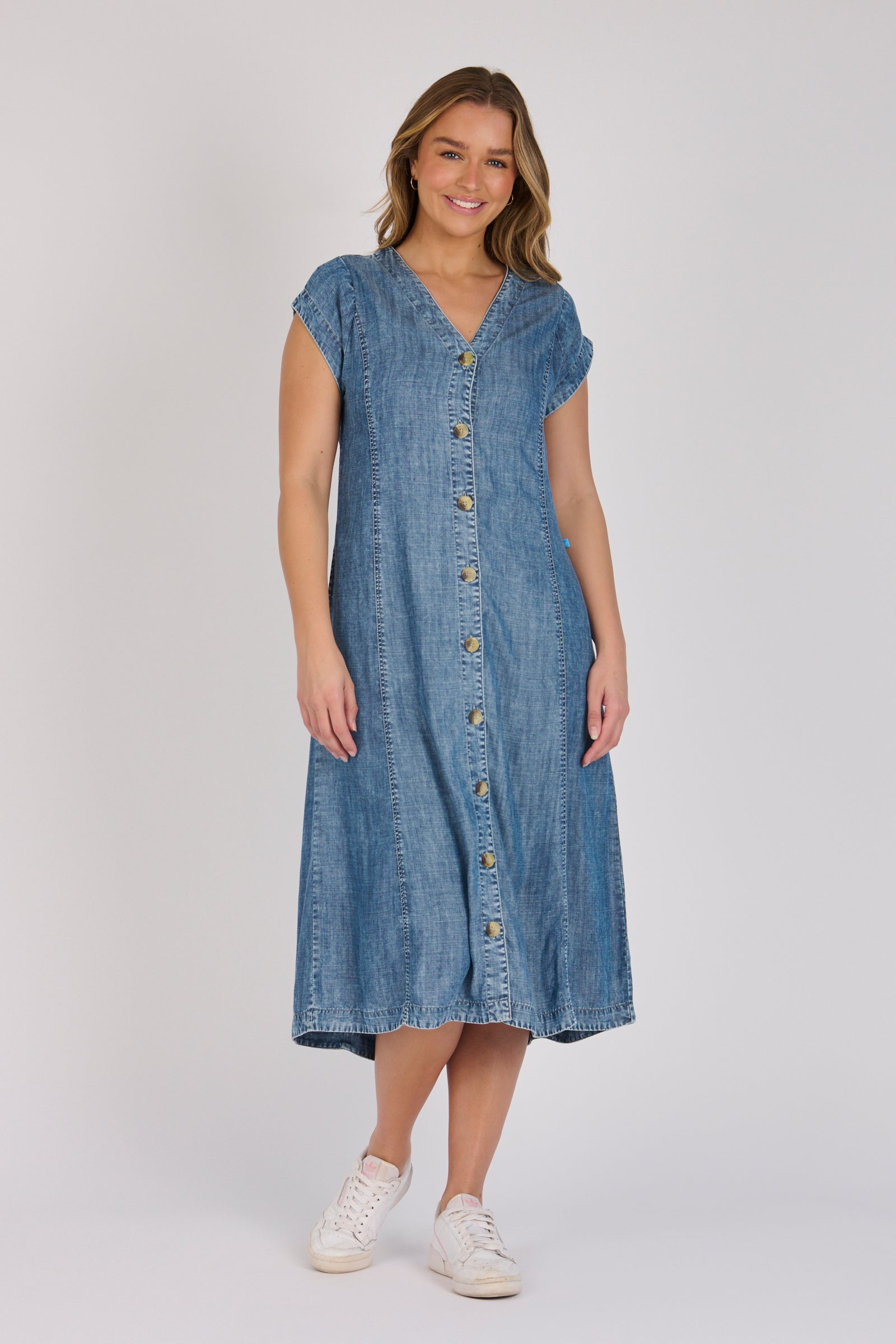 Woman wearing a dark blue 100% lyocell button-through midi dress with panelled seams and cap sleeves.