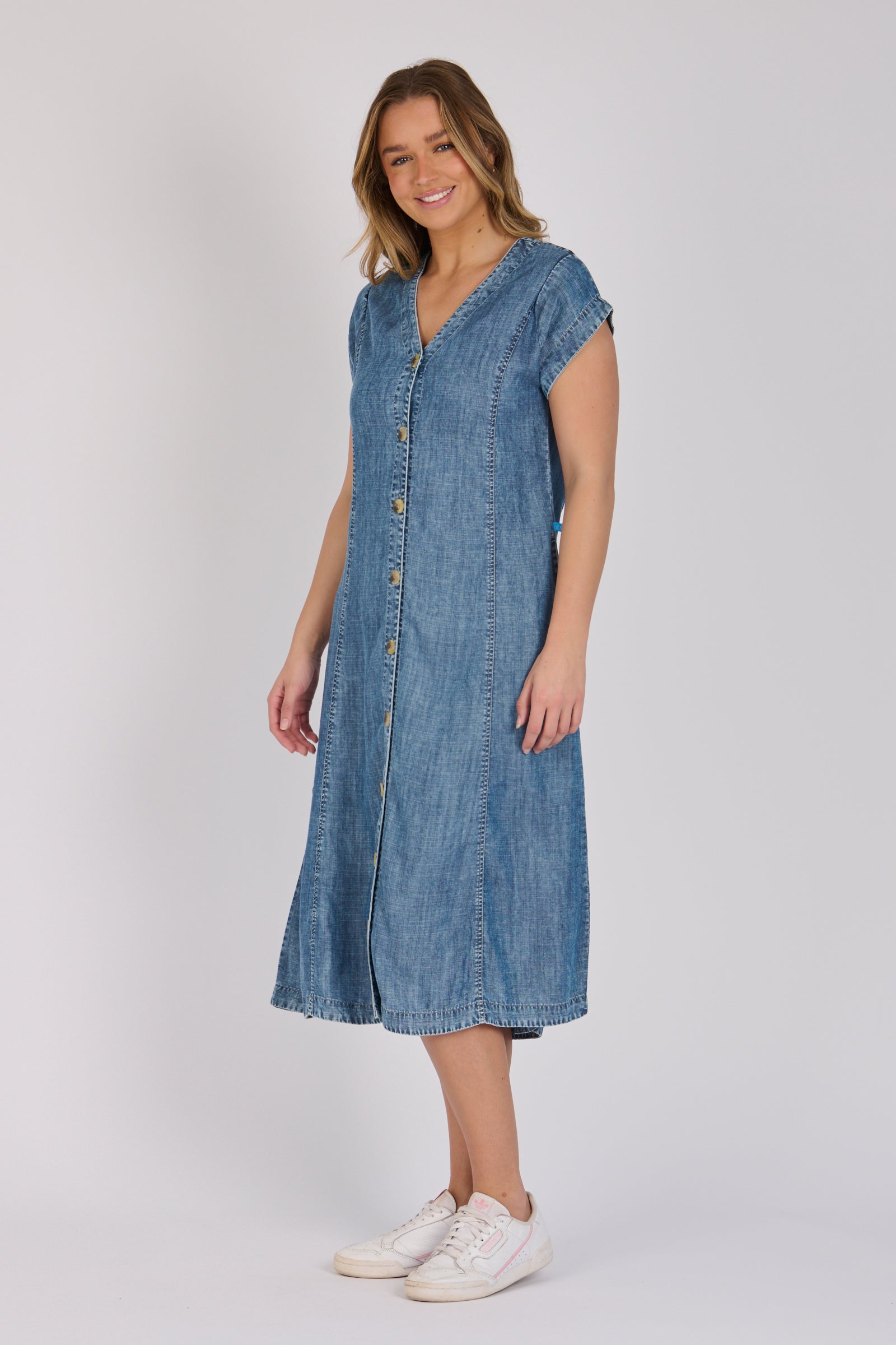 Woman wearing a dark blue 100% lyocell button-through midi dress with panelled seams and cap sleeves.