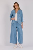 Woman wearing a light blue 100% lyocell utility jacket with patch pockets and a collarless neckline.