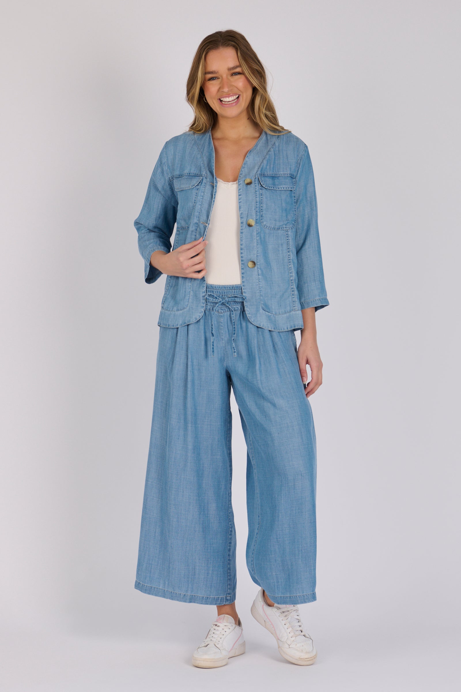 Woman wearing a light blue 100% lyocell utility jacket with patch pockets and a collarless neckline.