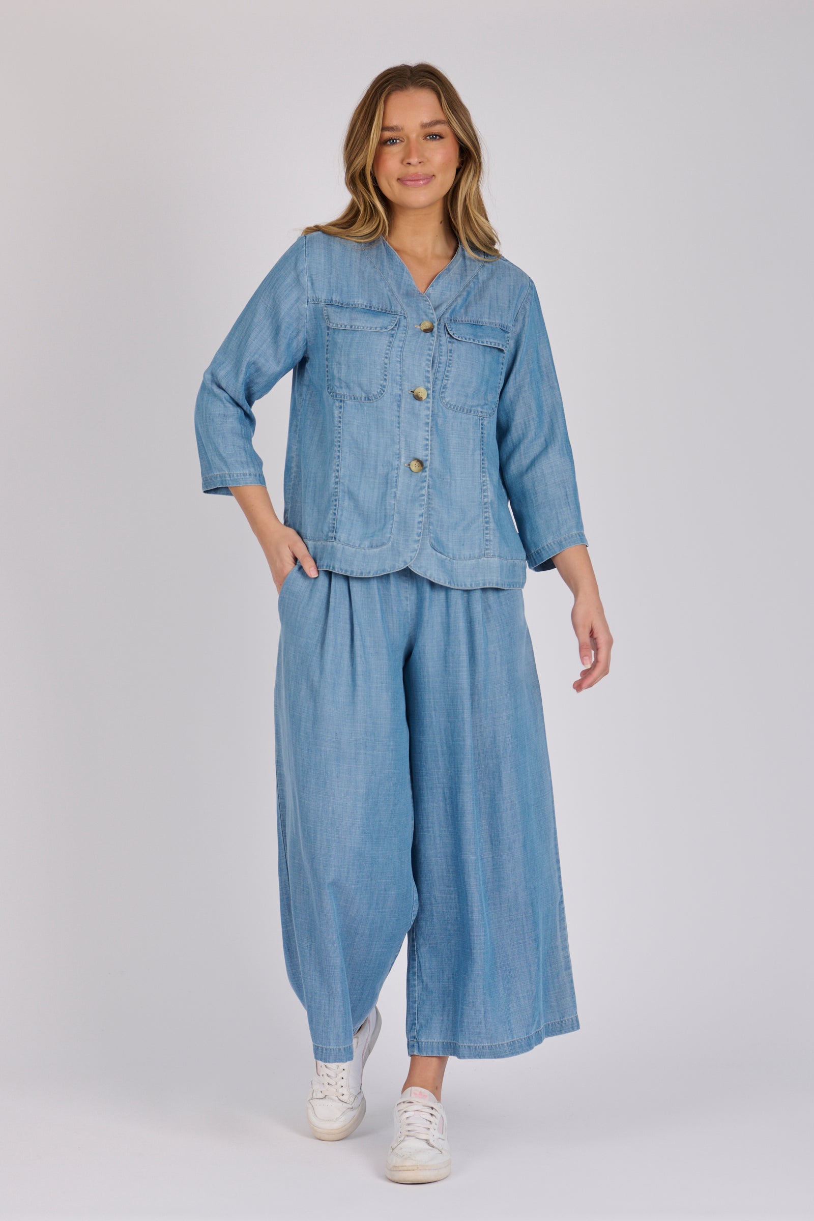 Woman wearing a light blue 100% lyocell utility jacket with patch pockets and a collarless neckline.