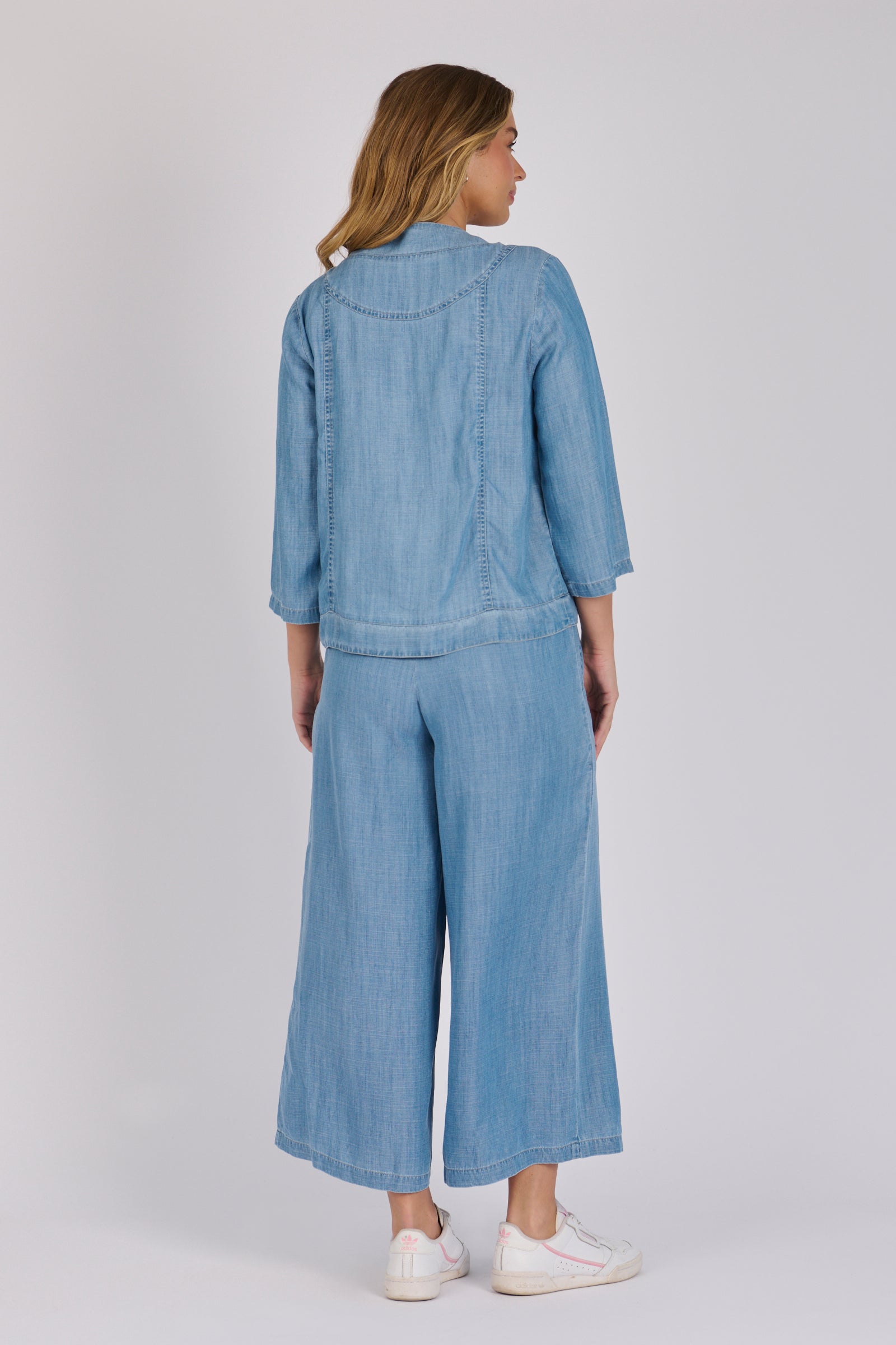 Woman wearing a light blue 100% lyocell utility jacket with patch pockets and a collarless neckline.