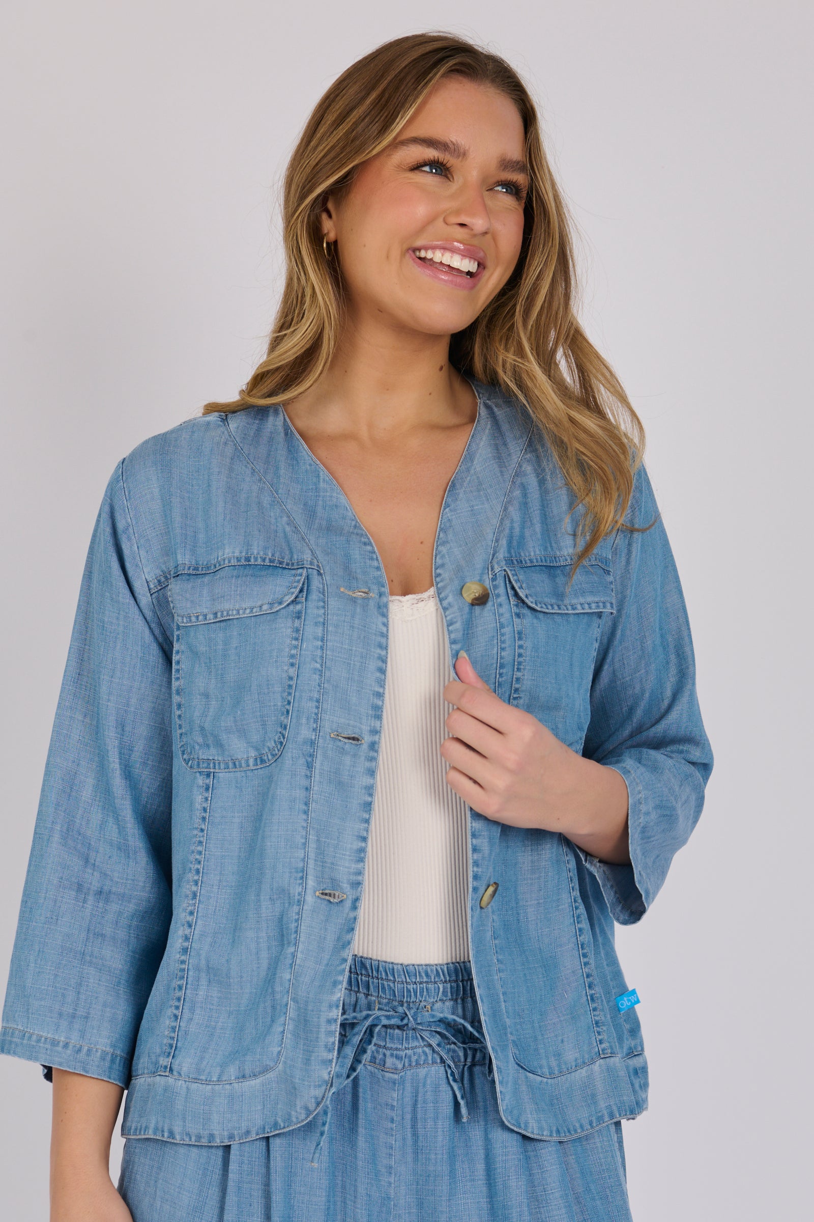 Woman wearing a light blue 100% lyocell utility jacket with patch pockets and a collarless neckline.