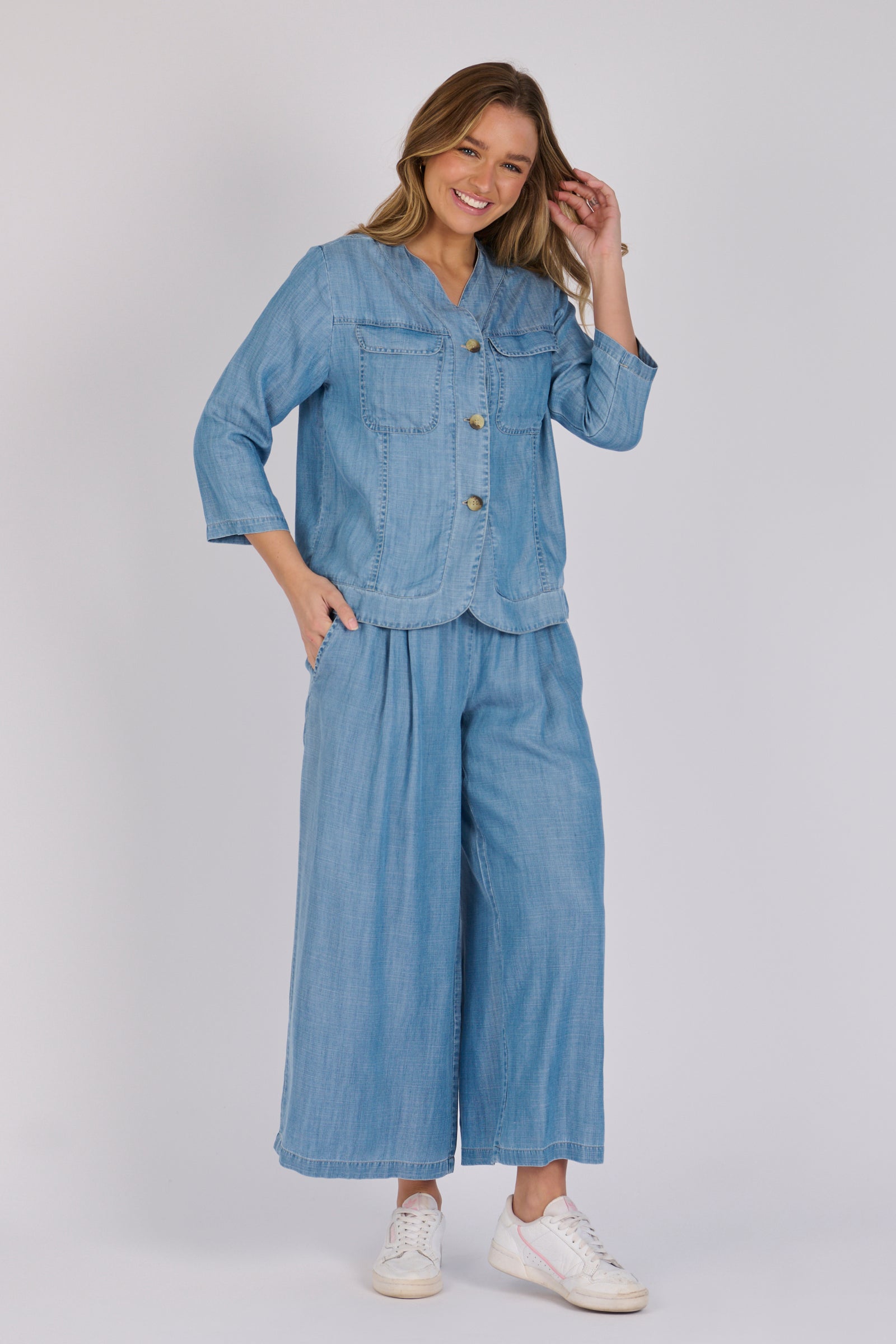 Woman wearing a light blue 100% lyocell utility jacket with patch pockets and a collarless neckline.