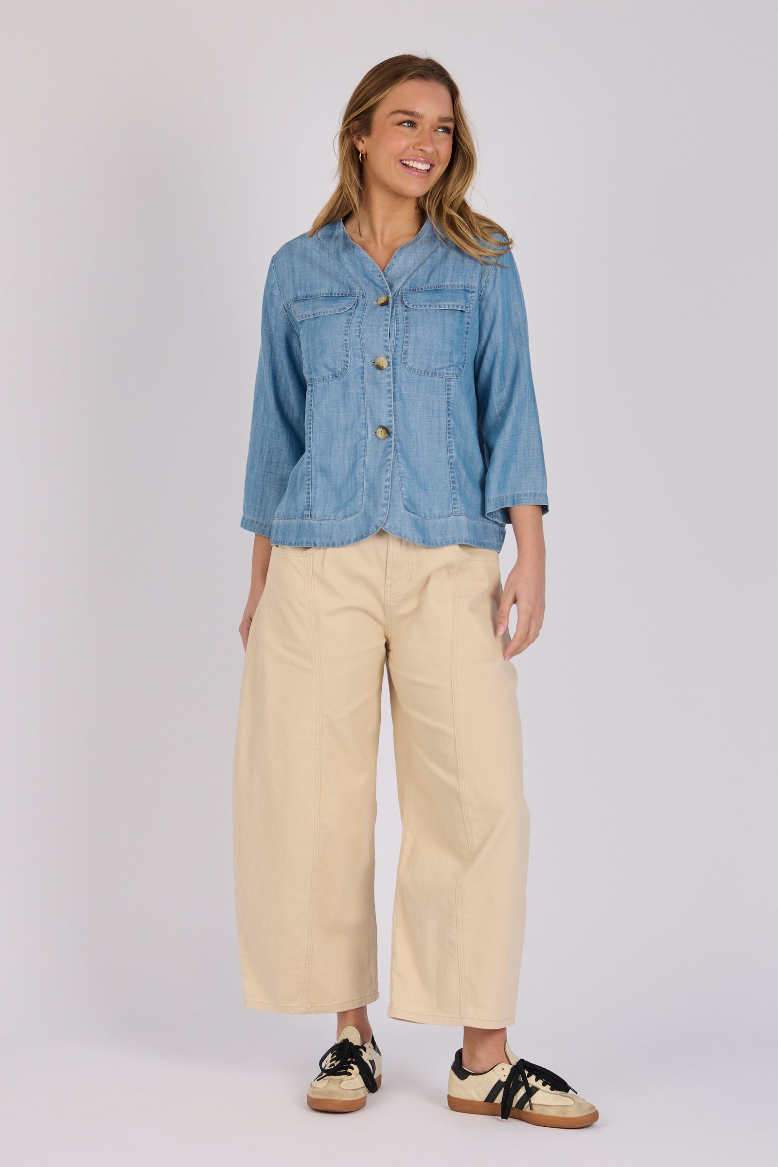 Woman wearing a light blue 100% lyocell utility jacket with patch pockets and a collarless neckline.