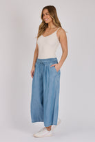 Woman wearing light blue 100% lyocell wide-leg pull-on pants with an elasticated waistband and side pockets.