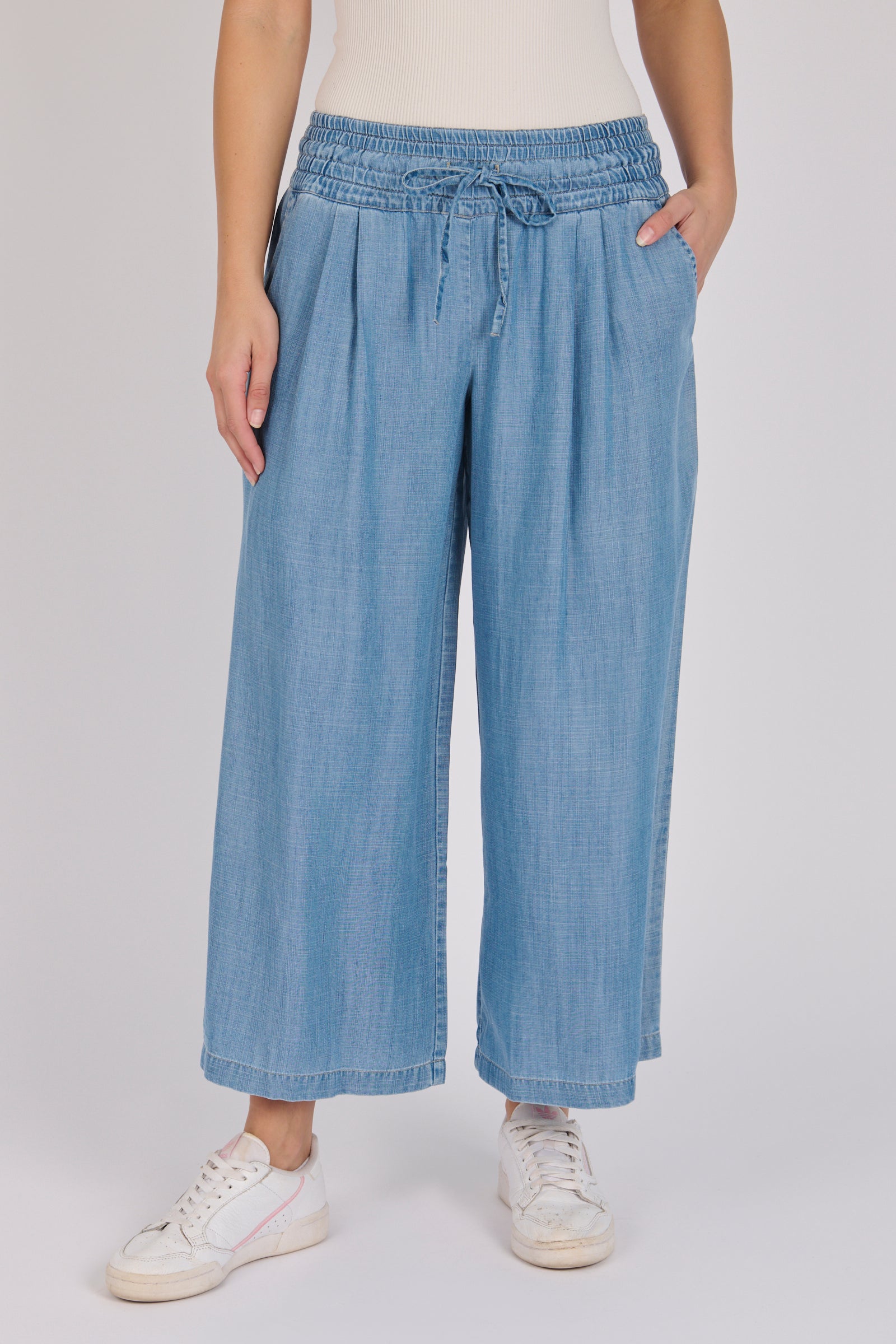 Woman wearing light blue 100% lyocell wide-leg pull-on pants with an elasticated waistband and side pockets.