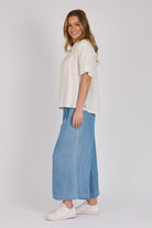 Woman wearing a white 100% lyocell short sleeve button-through shirt with cuffed sleeves and front panel detailing.
