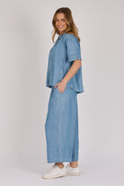 Woman wearing a white 100% lyocell short sleeve button-through shirt with cuffed sleeves and front panel detailing.