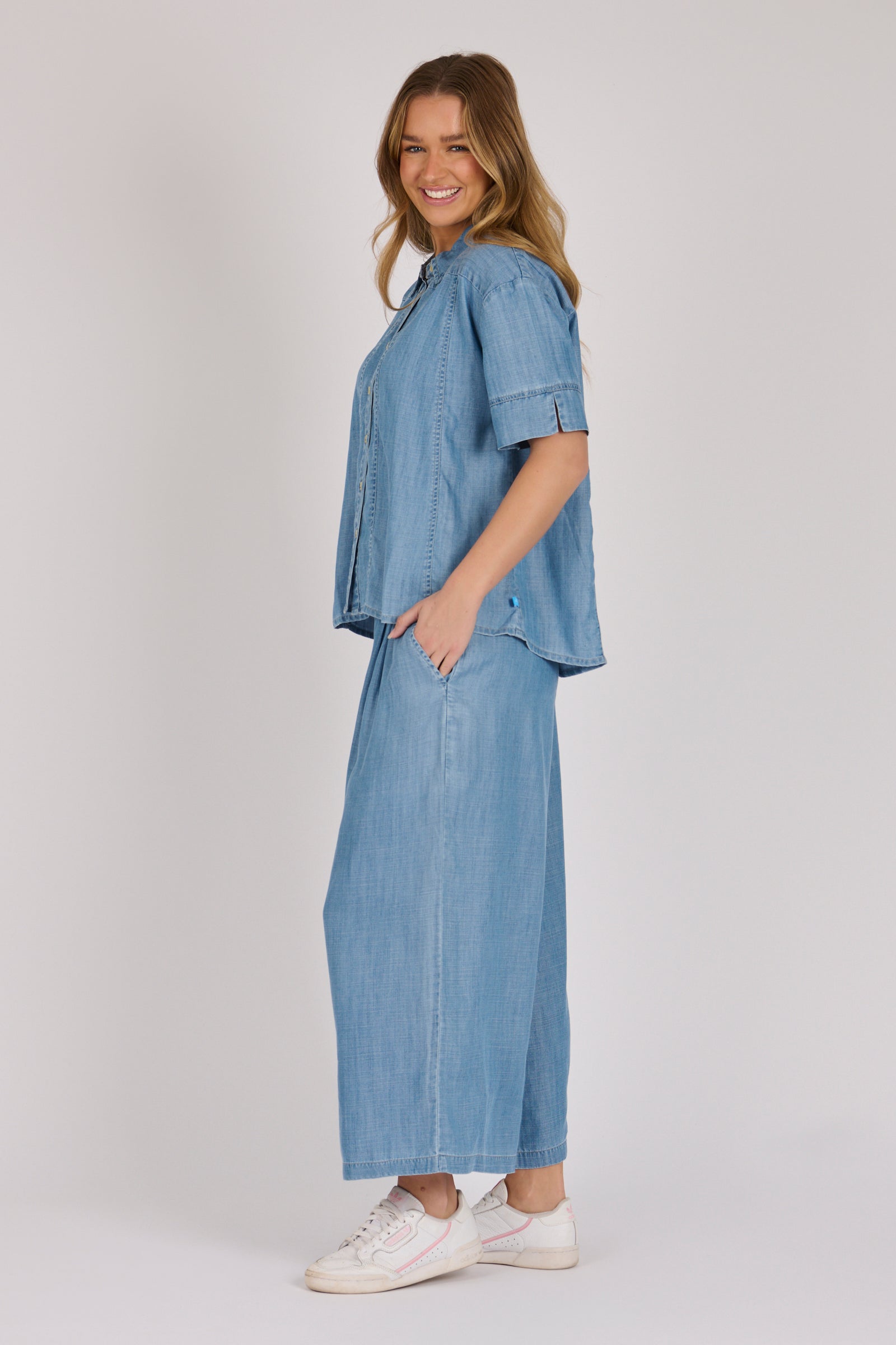 Woman wearing a white 100% lyocell short sleeve button-through shirt with cuffed sleeves and front panel detailing.