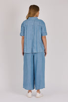 Woman wearing a white 100% lyocell short sleeve button-through shirt with cuffed sleeves and front panel detailing.