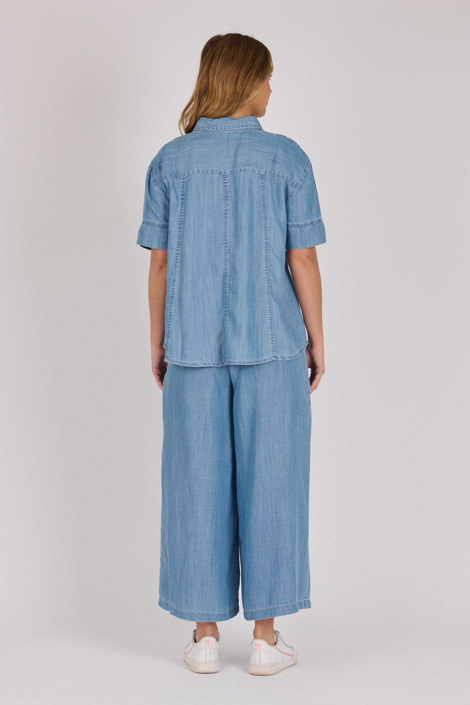 Woman wearing a white 100% lyocell short sleeve button-through shirt with cuffed sleeves and front panel detailing.