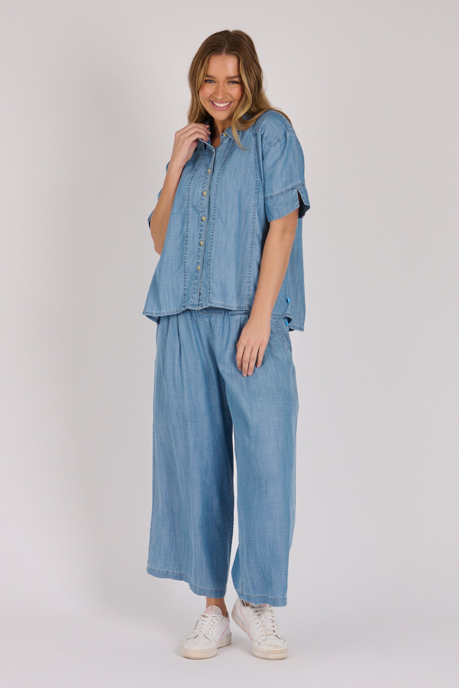 Woman wearing a white 100% lyocell short sleeve button-through shirt with cuffed sleeves and front panel detailing.