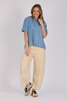 Woman wearing a white 100% lyocell short sleeve button-through shirt with cuffed sleeves and front panel detailing.