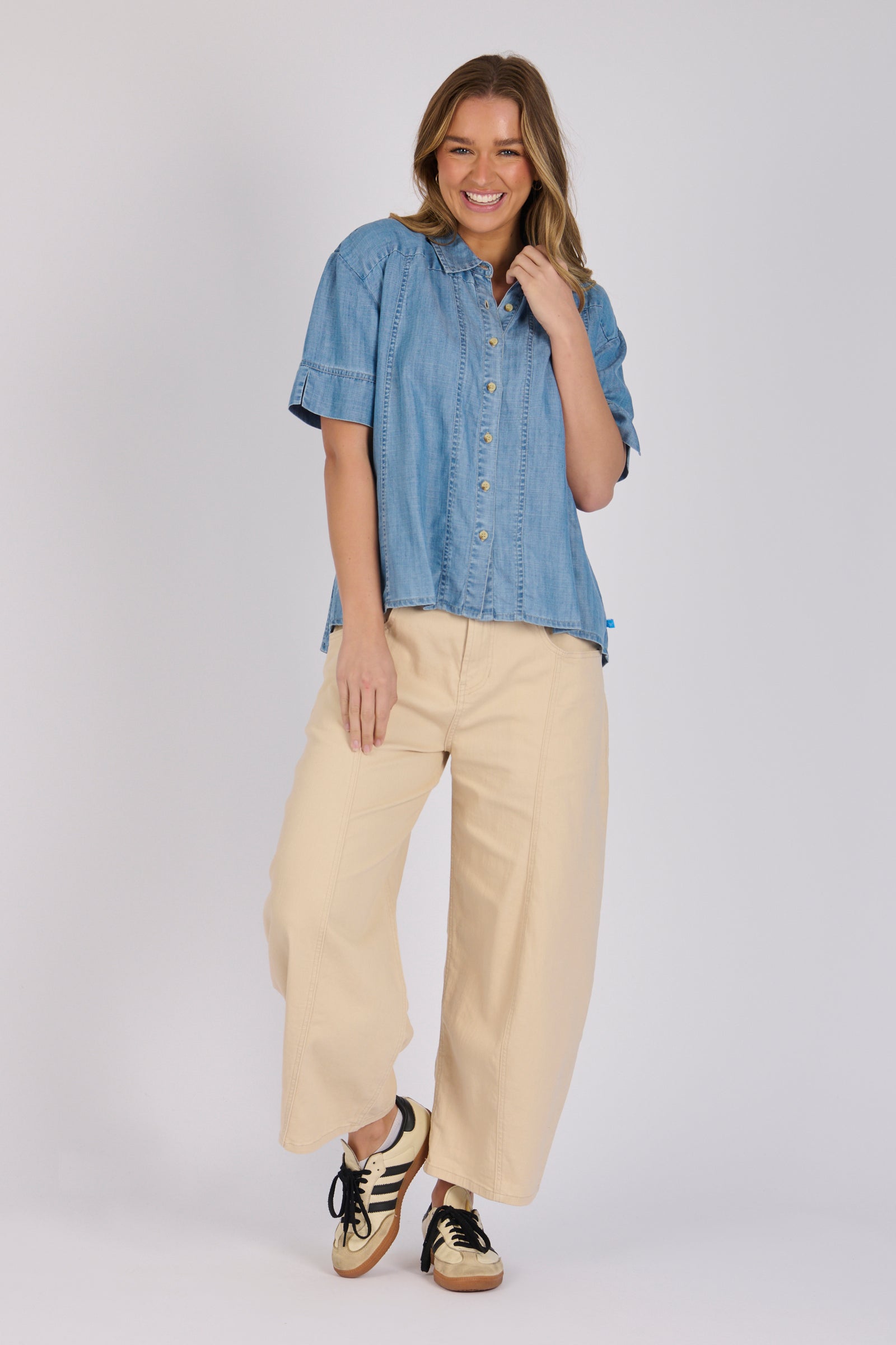 Woman wearing a white 100% lyocell short sleeve button-through shirt with cuffed sleeves and front panel detailing.