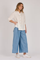Woman wearing a white 100% lyocell gathered waist blouse with vertical panel detailing, 3/4 elasticated sleeves and a button-through front.