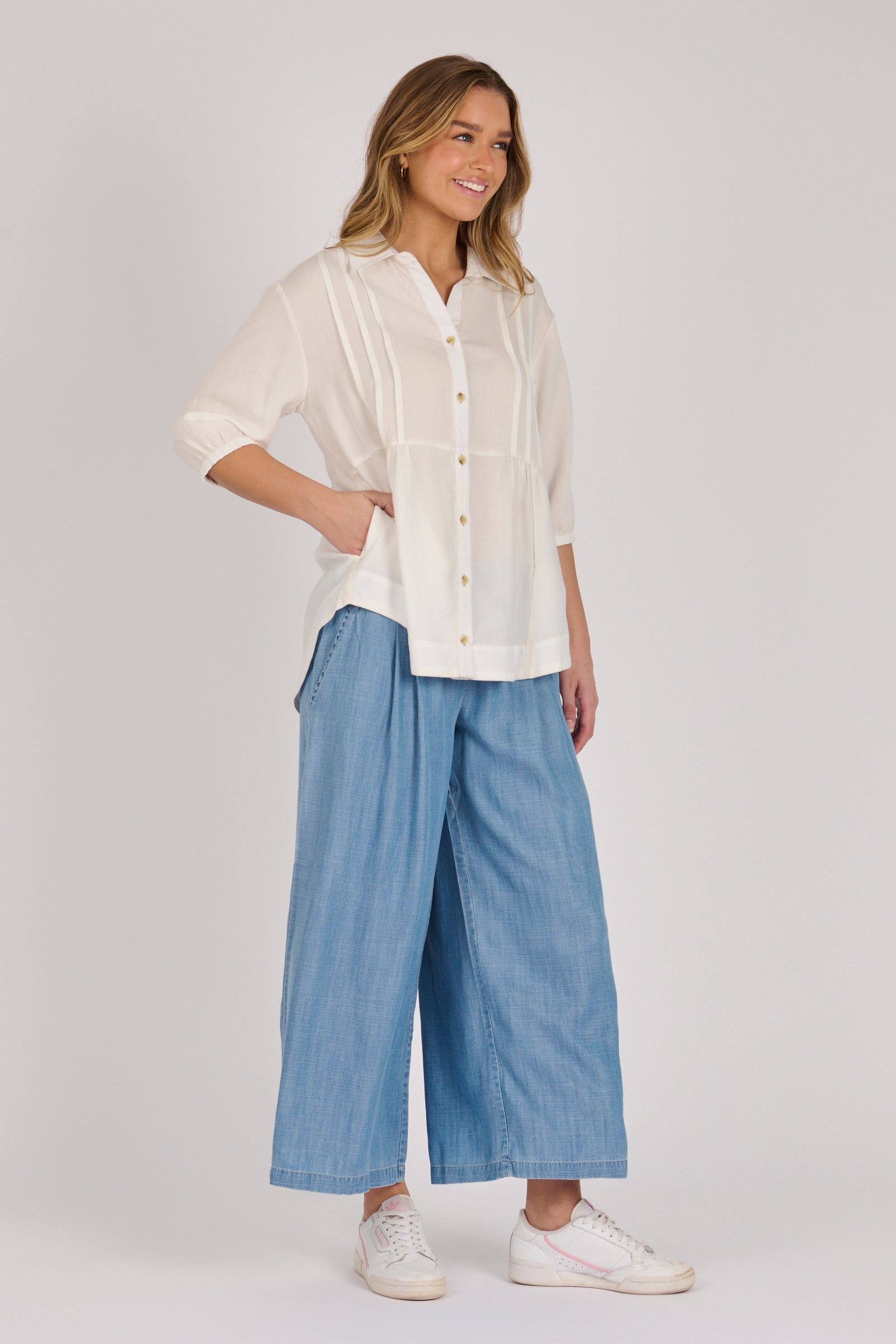 Woman wearing a white 100% lyocell gathered waist blouse with vertical panel detailing, 3/4 elasticated sleeves and a button-through front.
