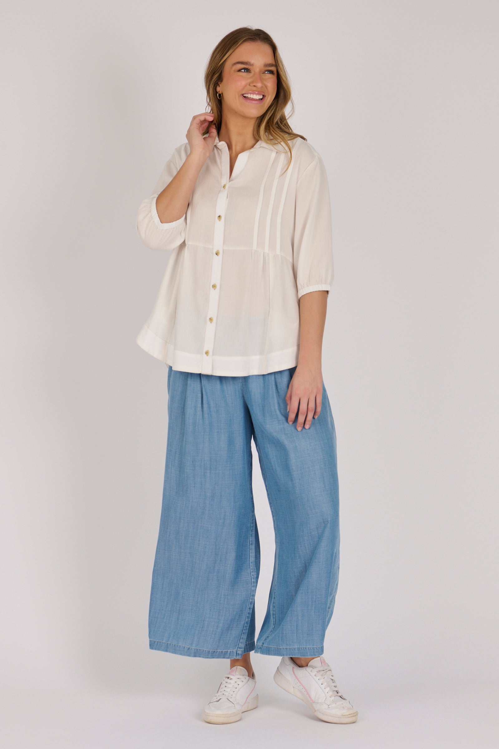 Woman wearing a white 100% lyocell gathered waist blouse with vertical panel detailing, 3/4 elasticated sleeves and a button-through front.