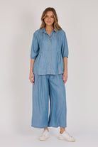 Woman wearing a light blue 100% lyocell gathered waist blouse with vertical panel detailing, 3/4 elasticated sleeves and a button-through front.