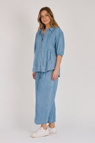 Woman wearing a light blue 100% lyocell gathered waist blouse with vertical panel detailing, 3/4 elasticated sleeves and a button-through front.