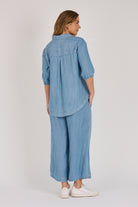 Woman wearing a light blue 100% lyocell gathered waist blouse with vertical panel detailing, 3/4 elasticated sleeves and a button-through front.