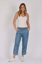 Woman wearing dark blue 100% lyocell beach pants with contrast piping, patch pockets and a relaxed tapered leg.