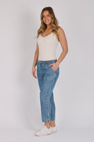 Woman wearing dark blue 100% lyocell beach pants with contrast piping, patch pockets and a relaxed tapered leg.