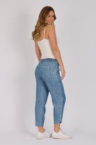 Woman wearing dark blue 100% lyocell beach pants with contrast piping, patch pockets and a relaxed tapered leg.
