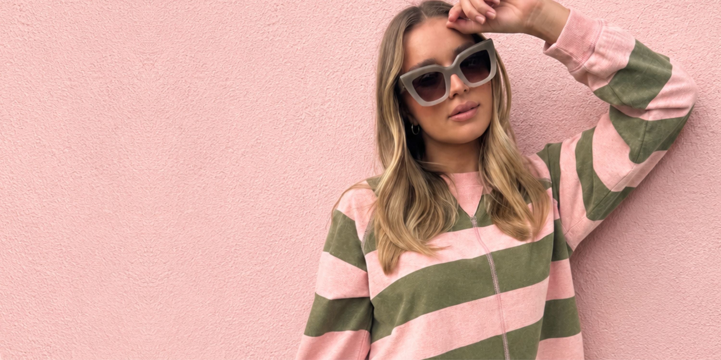 Woman wearing a pink and green striped sweater against a pink background